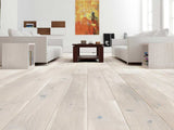 Modern living room with light wood flooring, white walls, and a colorful abstract painting.