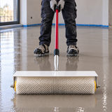 Installer using a XEPA spiked roller with extension pole on wet floor levelling compound